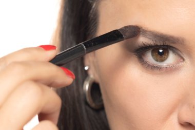 Makyaj fırçasıyla kaş çizen bir kadın..