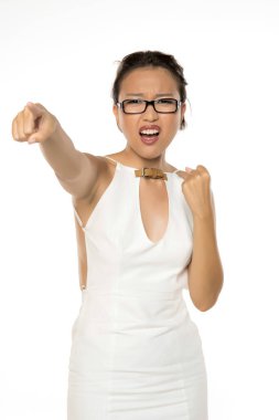 Beyaz elbiseli, yakalı, gözlüklü enerjik bir Asyalı kadın. Muzaffer bir jestle yumruğunu kaldırıyor, ünlemle ağzını açıyor. Beyaz arkaplan karşısında stüdyo görüntüsü.