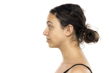 Makyajsız genç bir kadının profili. Doğal görünüş, siyah kıvırcık saçlar. Tarafsız ifade, geleceğe bakıyor. Beyaz arkaplanda stüdyo resmi.