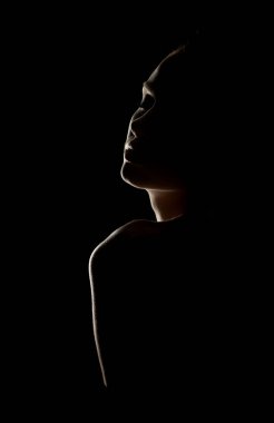 Profildeki dramatik kadın silueti. Gösterişsiz ışıklandırma hatları ve kıvrımları. Artistik çıplak fotoğraf konsepti ve minimum arkaplan.