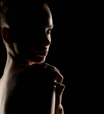 Profildeki dramatik kadın silueti. Gösterişsiz ışıklandırma hatları ve kıvrımları. Artistik çıplak fotoğraf konsepti ve minimum arkaplan.