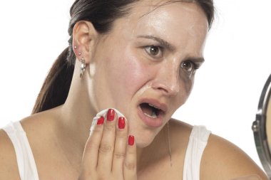 Gergin genç kadın beyaz stüdyo arka planındaki makyajı kaldırıyor.