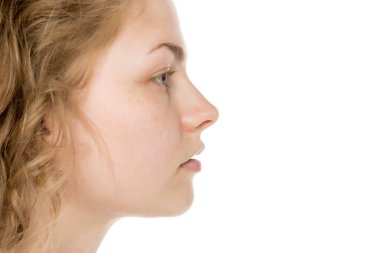 Uzun kıvırcık sarı saçlı, dalgın dalgın bakan genç bir kadının yan görünümü. Makyaj yok, beyaz arkaplanda izole edilmiş.