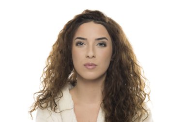 Beyaz bornozlu, kıvırcık kahverengi saçlı, beyaz arka planda kendine güveni olan, doğal güzelliği olan, sofistike portresi olan bir kadın..