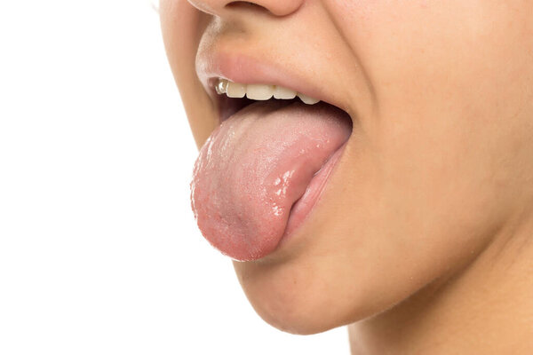Close-up of female mouth with tongue out, showing teeth and expressive gesture. Playful, candid moment captured in studio with minimal white background.