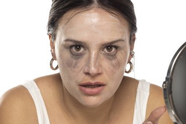 Beyaz stüdyo arka planında çıkarmadan önce genç sinirli kadın yüz temizleme ürünüyle poz veriyor.