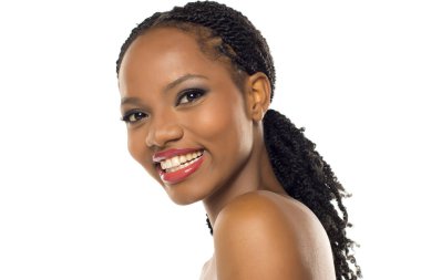 Makyajlı, beyaz arka planda gülümseyen ve başını eğen siyahi bir kadının stüdyo fotoğrafı..