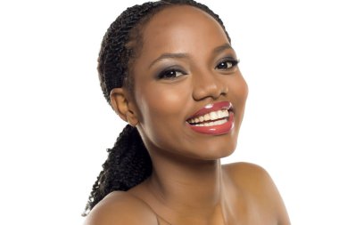 Makyajlı, beyaz arka planda gülümseyen ve başını eğen siyahi bir kadının stüdyo fotoğrafı..