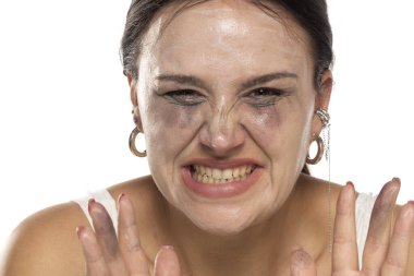 Makyaj ve kirli ellerle yüzünü buruşturan kadın, başarısız cilt bakımı ya da makyaj temizleme konsepti, beyaz arka planda stüdyo çekimi