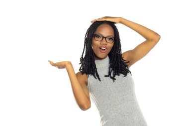 Stüdyo, bir eli gözlüklü, beyaz arka planda, bir eli kafasında, bir yandan da bir ürünü tanıtır ya da tanıtırmış gibi el kol hareketi yapan siyahi bir kadının beyaz arkaplanını çekiyor..