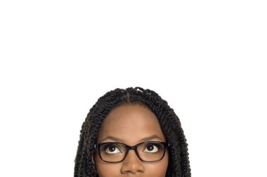 Gözlüklü, tuhaf bir ifadeyle yukarı bakan, beyaz arka planda çekim yapan siyahi bir kadının yakın çekimi.