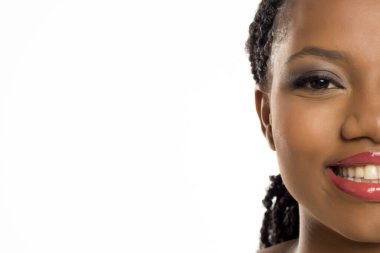 Yüzünde zarif makyajla gülümseyen siyahi bir kadının yarı resmi, beyaz arka planda stüdyo çekimi..