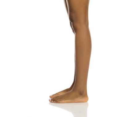 Çıplak bacakların ve ayakların yan görüntüsü, zarif duran siyah bir kadının, beyaz arka planda stüdyo çekimi