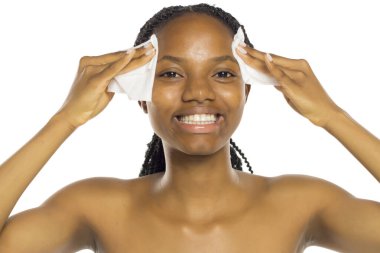 Yüzünü ıslak mendille temizlerken gülümseyen siyah kadın, beyaz arka planda stüdyo çekimi..