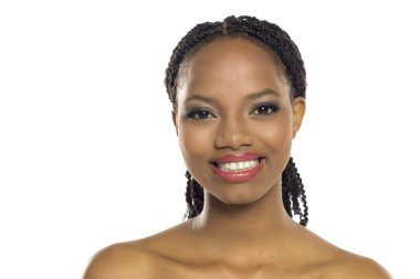 Makyajlı, özgüvenle gülümseyen siyah bir kadının portresi, beyaz arka planda stüdyo çekimi..