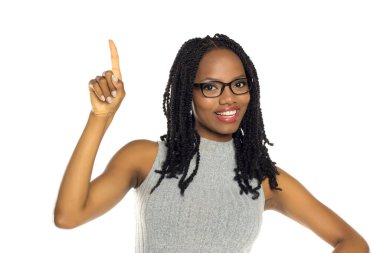 Gözlüklü, gri elbiseli, beyaz arka planda stüdyo resmi olan gülümseyen siyahi kadın.