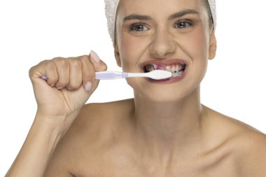 Genç bir kadın sabah rutininde dişlerini fırçalıyor ve gülümsüyor.