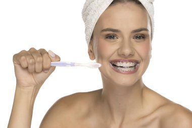 Dişlerini fırçalayan ve köpükle gülümseyen genç bir kadın.