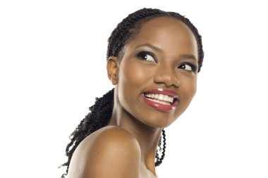 Makyajlı siyahi bir kadının beyaz arka planda gülümseyip bakışlarını kaçırdığı bir stüdyo resmi..