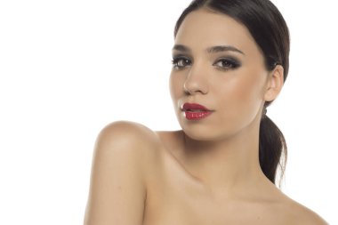 Dramatik makyajlı, kırmızı dudaklı, kameraya bakan baştan çıkarıcı bir kadın.