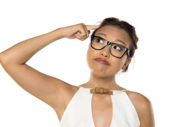 Kafasını gösteren gözlüklü kafası karışmış bir kadın. Düşünen bir yüz ifadesi. Beyaz arka planda stüdyo çekimi.