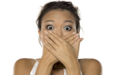 Beyaz arka plandaki stüdyo çekimlerinde, Asyalı bir kadının şok ve utanç içinde ağzını kapattığı görülüyor.