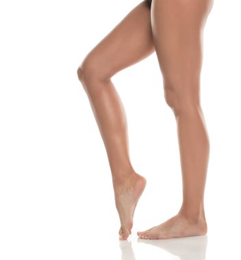 Kadın bacakları ve ayakları parmak uçlarında, pürüzsüz cilt ve hareketli zarafet, beyaz arkaplan