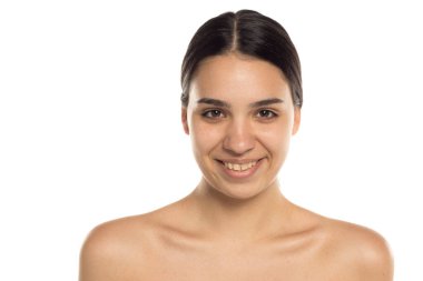 Beyaz arka planda doğal gülüşü olan genç bir kadının stüdyo çekimi.