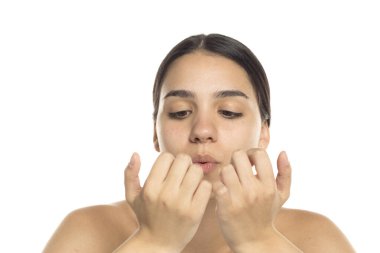 Genç bir kadının beyaz arka planda yeni yapılmış tırnaklarına üflediği bir resim.