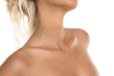 Kadının çıplak omuzları ve boynu pürüzsüz bir ten ve zarif bir duruş sergiliyor. Beyaz arka planda stüdyo çekimi..