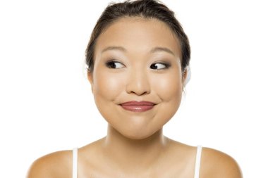 Beyaz stüdyo arka planında makyajlı gülümseyen genç bir Asyalı kadının portresi.