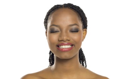 Gözleri kapalı ve büyüleyici makyajlı gülümseyen siyah bir kadının portresi, beyaz arka planda stüdyo çekimi..