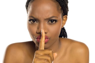 Kızgın siyahi kadın yoğun bir ifadeyle sessiz jest yapıyor, beyaz arka planda stüdyo çekimi.