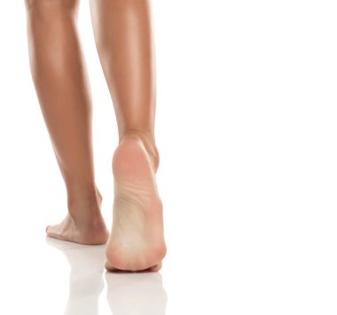 Çıplak ayakla yürüyen kadınların aşırı yakın çekimi, topuk ve deri dokusuna odaklanma, beyaz arka planda stüdyo çekimi.