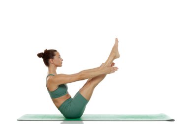 Tudio çekiminde kadın beyaz arka planda yoga pozu veriyor.