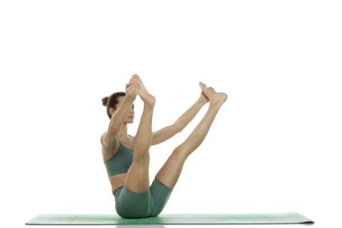 Yeşil elbiseli genç bir kadının beyaz arka planda yoga pozu (upavistha konasana versiyonu) çalışırken çekilen çekimleri.