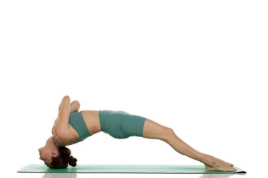 Yeşil elbiseli genç bir kadının, beyaz arka planda destekli briç pozu uygulaması çekimleri.