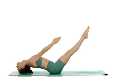 Stüdyoda, yeşil elbiseli genç bir kadının beyaz arka planda yükseltilmiş bacakları ve kolları (uttana padasana) olan balık pozu çekimleri.