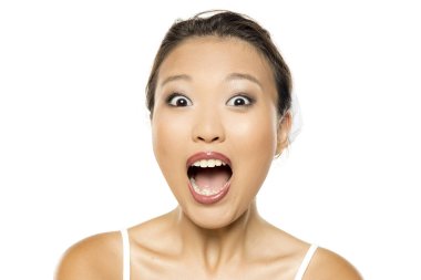 Makyajlı bir Asyalı kadın, şaşırmış bir ifade sergiliyor, ağzı açık, beyaz arka planda stüdyo çekimi var.