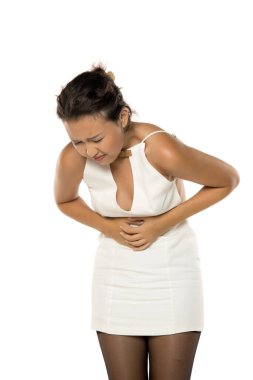 Karnı ağrıyan Asyalı bir kadın, beyaz arka planda stüdyo çekimi.