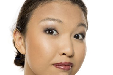 Makyajlı Asyalı kadının şüpheli bir yüz ifadesi, beyaz arka planda stüdyo çekimi.