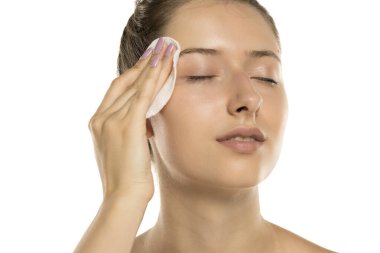 Makyajsız, beyaz arka planda pamuk yastıklı genç bir kadının stüdyo fotoğrafı.