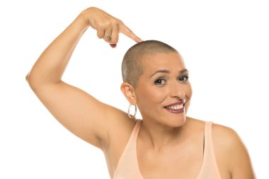 Hafif kolsuz tişörtlü kel kadının beyaz arka planda başını gösteren bir stüdyo resmi.