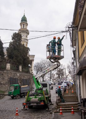 Uzhhorod, Ukraine - December 21,2022: Electricians climbing to fix and repair power line in Uzhhorod, Ukraine
