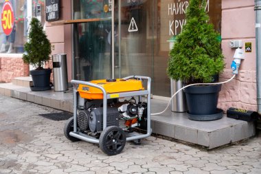 Uzhhorod, Ukraine - December 25, 2022: Cafes and shops are forced to use electricity from portable gasoline generators because of the lack of electricity. Power supply generator is placed on the street sidewalk in Uzhhorod, Ukraine