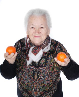Yaşlı gülümseyen kadın elinde mandalinalarla stüdyoda beyaz arka planda poz veriyor.