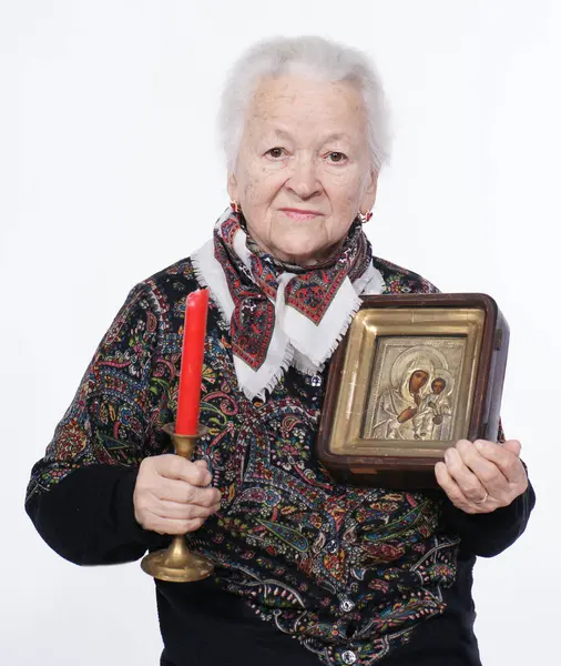 Portrait of old woman with icon posing in studio over white background