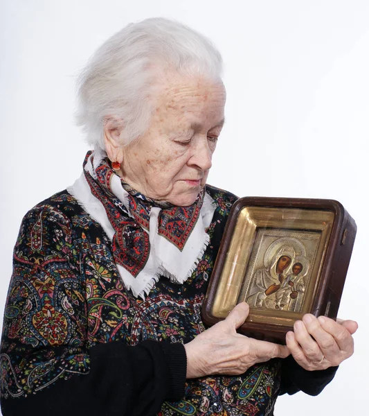 Portrait of old woman with icon posing in studio over white background