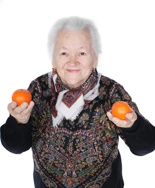 Yaşlı gülümseyen kadın elinde mandalinalarla stüdyoda beyaz arka planda poz veriyor.