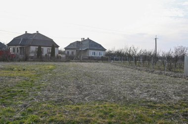 Boş arazili kırsal alan ve öğleden sonra saatlerinde sessiz bir ortamda evler. 